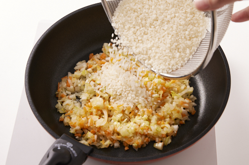 米を目の細かいザルに入れ振るい、ごみなどを落としてから、洗わずに2.に加え、米が透き通るまで炒める。
